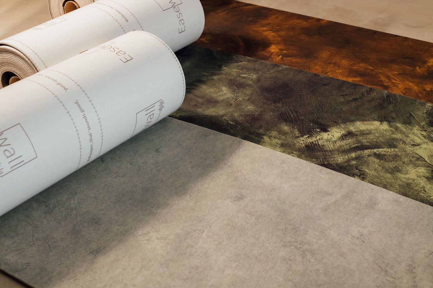 Easewall Raw Copper, Forest and Dust designs rolls rolled out over the floor showing designs