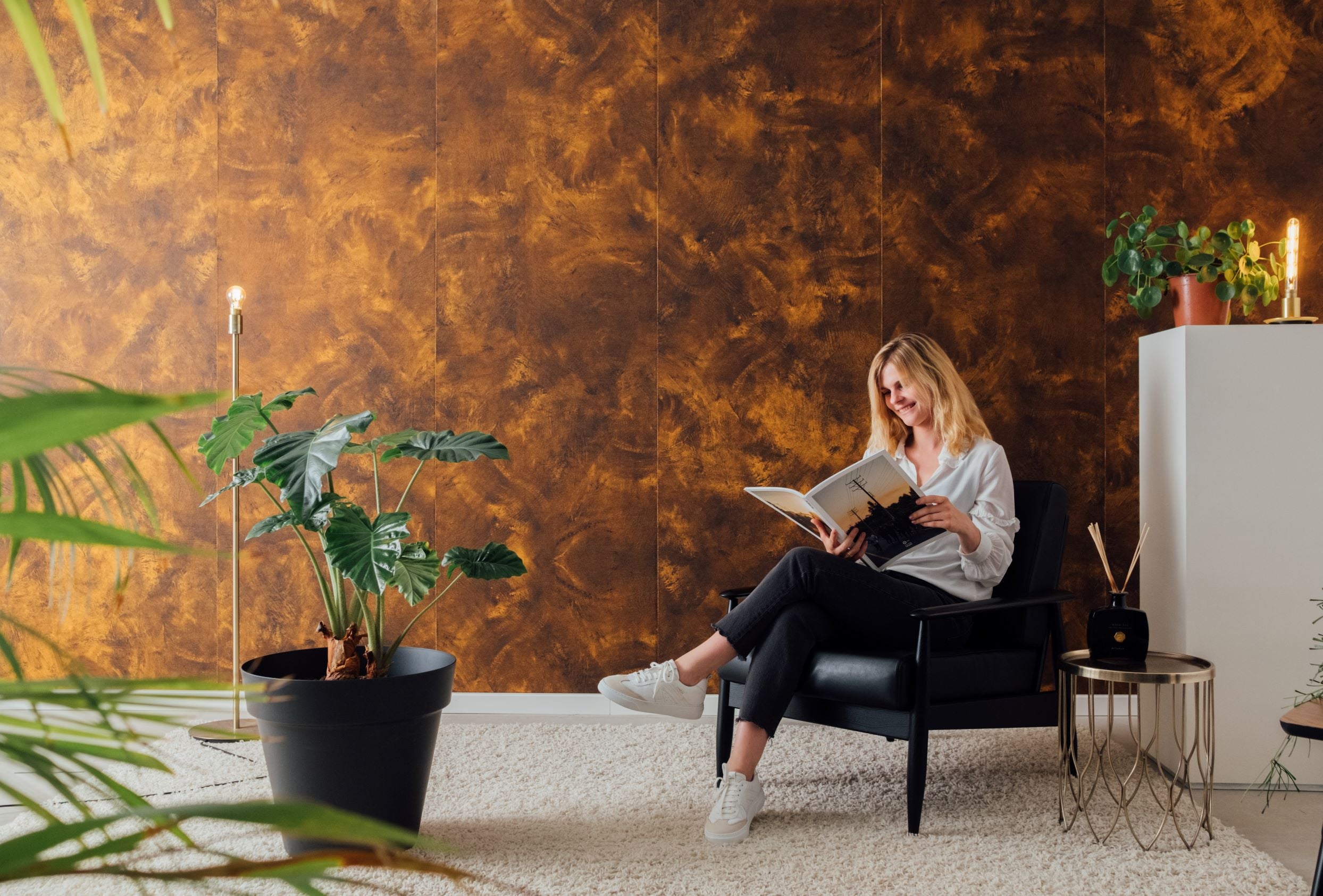 Woman reading a magazine in cozy chair Easewall acoustic wallpaper Raw Copper